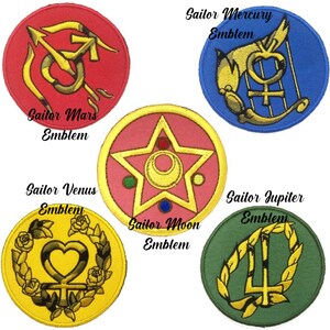 May include: Five embroidered patches featuring Sailor Moon emblems. Each patch is circular with a different color background and a unique design. The patches include Sailor Mars, Mercury, Venus, Moon, and Jupiter emblems, with text labels.