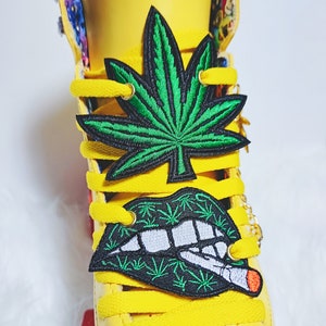 May include: Yellow roller skate with green marijuana leaf and a black and white lips with a cigarette patch on the laces.