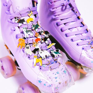 May include: Purple roller skates with a clear, star-shaped toe stop. The laces are decorated with a variety of small dog charms.