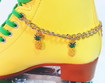 Peut inclure: Patin à roulettes jaune avec des lacets verts et une chaîne dorée avec des breloques en forme d'ananas. Le patin a des roues vertes.