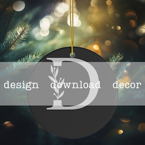 May include: Black and white Christmas ornament with a white letter D and a small floral design. The ornament is hanging from a gold string.