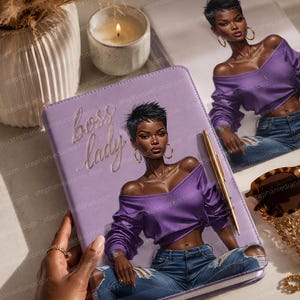 May include: A lavender journal with the words "boss lady" in gold script. The cover features an illustration of a woman in a purple top and jeans. A gold pen rests on the journal, and a pair of sunglasses is nearby.