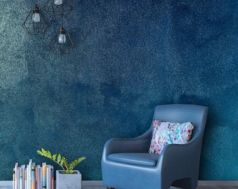 Könnte beinhalten: Ein blauer Sessel mit einem gemusterten Kissen steht vor einer blauen Wand mit strukturierter Oberfläche. Drei hängende Leuchten mit käfigartigen Schirmen sind in der oberen linken Ecke des Bildes zu sehen.