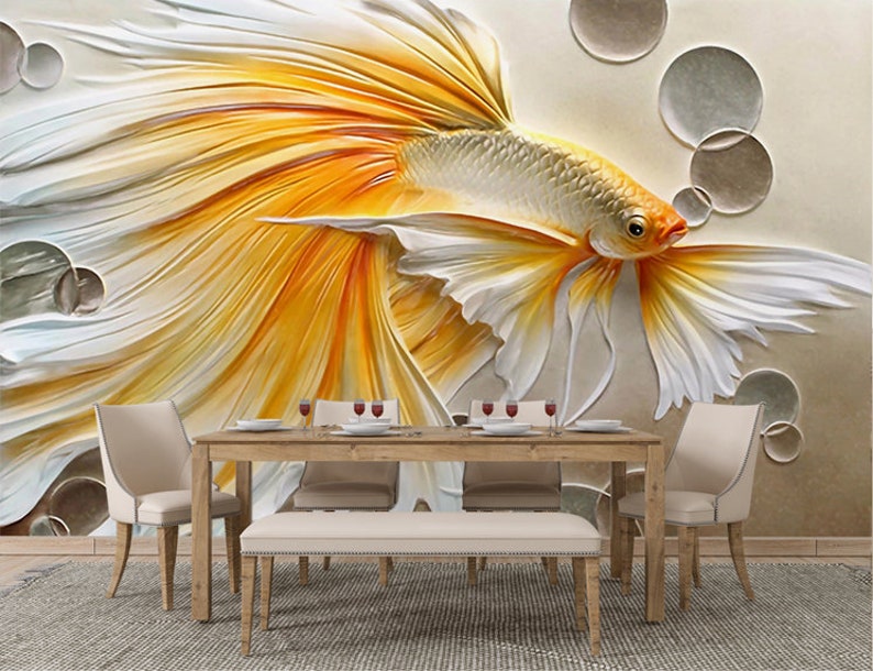 K&ouml;nnte beinhalten: Ein 3D-Wandbild mit einem stilisierten, wei&szlig;en und gelben Fisch mit flie&szlig;enden Flossen. Der Fisch ist vor einem Hintergrund aus Beige mit kreisf&ouml;rmigen Formen platziert.