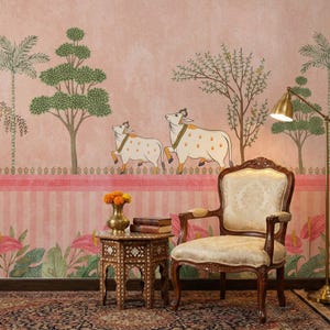 May include: A room with a pink and white striped wall featuring a mural of two cows, trees, and floral elements. A wooden chair with a patterned cushion, a small table with a vase of flowers, and a floor lamp are in the foreground.