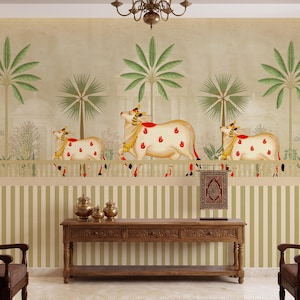 May include: A decorative wall mural featuring a cream-colored background with green palm trees and three cream-colored cows with red and gold accents. The lower portion of the wall has vertical green and white stripes. A wooden console table and decorative items are in front.