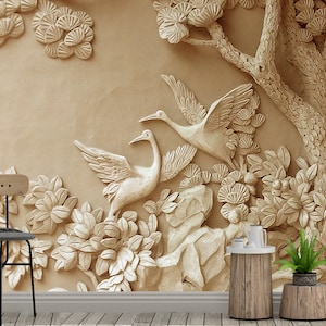 Könnte beinhalten: Eine beige 3D-Wandmalerei mit einem geschnitzten Design eines Baumes mit Ästen und Blättern, zwei Vögeln und Blumen. Die Wandmalerei befindet sich in einem Raum mit einem Holzstuhl und einem Holztisch mit einer Pflanze darauf.