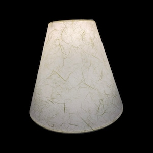 May include: A white lampshade with a textured, paper-like surface. The shade has a conical shape and a white fabric lining.