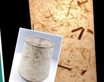 May include: A white lampshade with a textured, paper-like surface. The shade has a brown, metallic trim around the top edge.