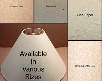 May include: A white lampshade with a conical shape and a gold metal top. The lampshade is made of a textured paper material. The text "Available In Various Sizes" is printed on the lampshade. The image also shows four samples of different paper textures: Cream Luster, Flex Paper, Rice Paper, and Cream Luster Lite.