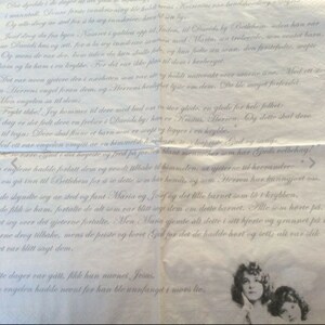 K&ouml;nnte beinhalten: Eine vintage, cremefarbene Papierserviette mit verblassten, handschriftlichen Text &uuml;ber die Geburt Jesu. Der Text ist in einer traditionellen Schriftart und enth&auml;lt die W&ouml;rter "Christus, Herren" und "F&uuml;rchte dich nicht!" Die Serviette zeigt ein Schwarzwei&szlig;bild einer Frau mit langen, dunklen Haaren und einem wei&szlig;en Kleid. Die Frau blickt nach oben und rechts, mit einem sanften Ausdruck in ihrem Gesicht.