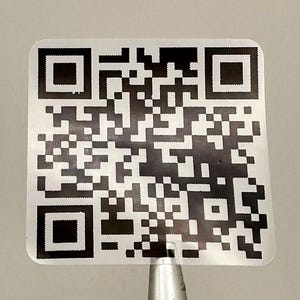 May include: A black and white square QR code sticker on a white background.