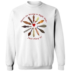 Puede incluir: Sudadera blanca con un corazón rojo y el texto "There's No Wrong or Right Way... Just Play it!" rodeado de un círculo de varios instrumentos musicales de madera.