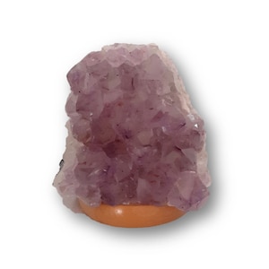 May include: A large amethyst crystal cluster with a purple and white color gradient. The crystal is sitting on a wooden base.
