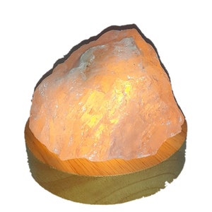 Könnte beinhalten: Eine klare, natürliche Kristallsalzleuchte mit einem warmen, glühenden Licht. Die Lampe steht auf einem Holzsockel.
