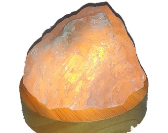 Könnte beinhalten: Eine klare, natürliche Kristallsalzleuchte mit einem warmen, glühenden Licht. Die Lampe steht auf einem Holzsockel.