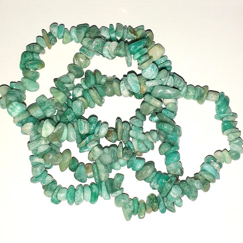 May include: A strand of green aventurine chip beads. The beads are irregular in shape and size, and they are strung together on a clear thread.