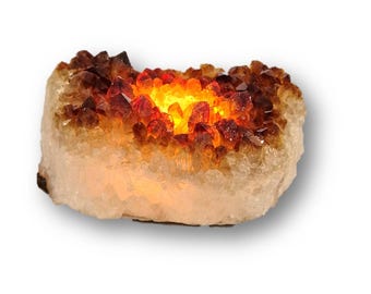 May include: A glowing citrine crystal cluster. The crystal features a warm, amber-colored interior that emits a bright, golden light. The outer edges of the crystal are a lighter, off-white color. The overall shape is rectangular.