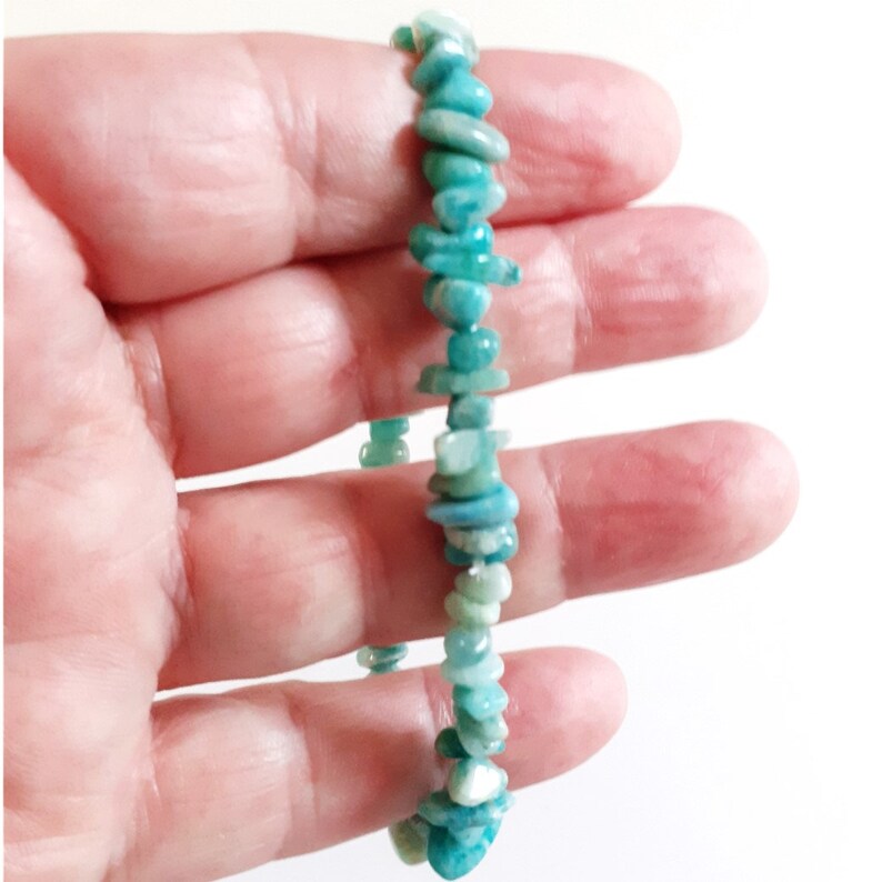 May include: A turquoise green chip bracelet made of natural stones. The bracelet is made of small, irregular shaped chips of turquoise green stone.