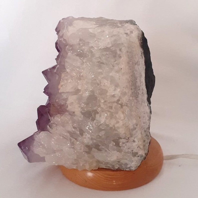 May include: A large amethyst crystal lamp with a wooden base. The crystal is clear with purple accents and has a natural, rough texture.