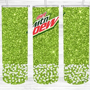 May include: Three green glitter tumbler cups with a white glitter bottom. The center cup has the words "diet mtn dew" in red and white.