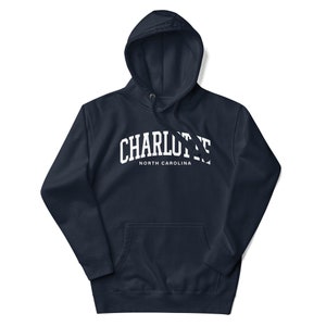 May include: A navy blue hooded sweatshirt with a white arch design that says "CHARLOTTE NORTH CAROLINA".