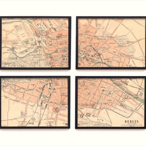 May include: Four framed vintage maps of Berlin, Germany. Each map is in black and white with pink and red accents. The maps are framed in black frames.