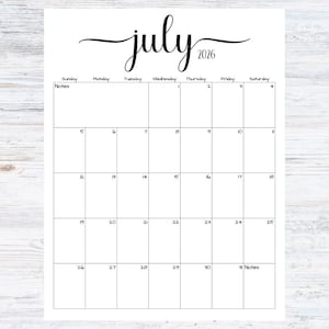 May include: A white calendar page for July 2026, with a cursive "july" at the top. The calendar grid includes dates from Sunday to Saturday, with space for notes. The background is a light wood grain.
