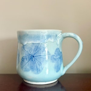 May include: A trio of ceramic mugs with a speckled, matte finish in cream, light grey, and dark grey. Each mug features a simple, minimalist design, ideal for tea or coffee.