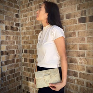 May include: A white leather crossbody bag with a silver chain strap. The bag has a flap closure with a silver buckle and a textured design.