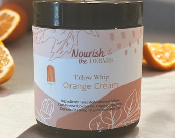 Può includere: Un barattolo di tallow whip alla crema d'arancia con un'etichetta rosa e bianca che dice "Nourish the Dermis Tallow Whip Orange Cream". L'etichetta elenca anche gli ingredienti: Sebo di bovini allevati a pascolo/finito, olio di jojoba spremuto a freddo, squalano biologico, cera d'api biologica, oli essenziali biologici.