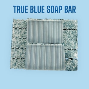 May include: Two bars of blue soap, one on top of the other, with a textured surface. The soap bars are surrounded by a blue and white patterned background.
