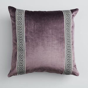 May include: A purple velvet pillow with a white and black Greek key design on the sides.