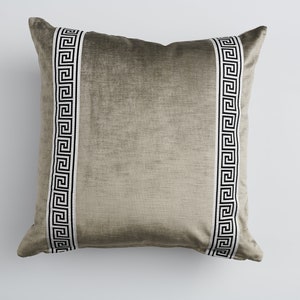 May include: A gray velvet pillow with black and white Greek key trim.