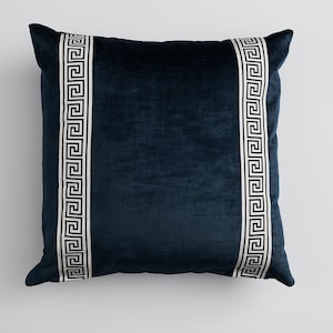 May include: A dark blue velvet pillow with white and black Greek key trim.