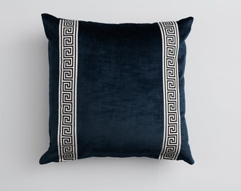 May include: A dark blue velvet pillow with white and black Greek key trim.
