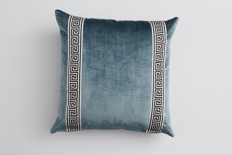 May include: A blue velvet pillow with white and black Greek key trim.