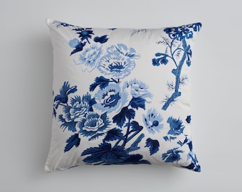May include: A white pillow with a blue floral pattern. The flowers are stylized and have a blue and white color scheme. The pillow is a decorative accent for a home.