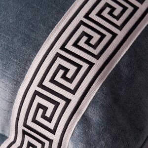May include: A blue velvet pillow with a white and black Greek key trim.