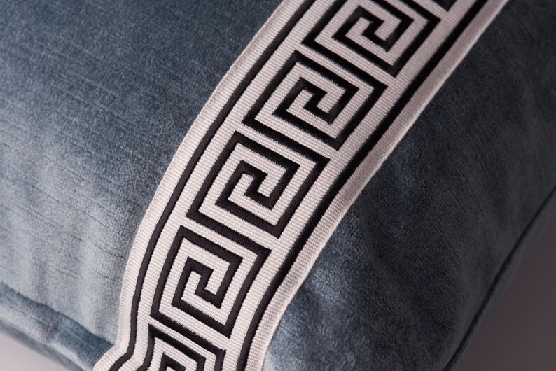 May include: A blue velvet pillow with a white and black Greek key trim.