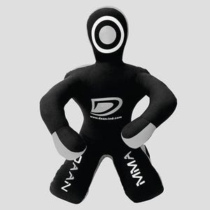 May include: Black and grey MMA training dummy with a white circular design on the head. The dummy has the text "DAAN" on one leg and "MMA" on the other. The logo and website www.daan-ind.com are visible on the chest.