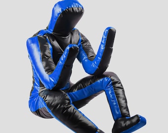 Könnte beinhalten: Eine blaue und schwarze Trainingspuppe in sitzender Position. Die Puppe ist so gestaltet, dass sie einer Person ähnelt, mit einer Kapuze, Armen, Beinen und Füßen. Das Design weist blaue Akzente an Armen, Beinen und Kopf auf.