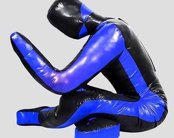 Könnte beinhalten: Eine schwarz-blaue Trainingspuppe in sitzender Position. Die Puppe besteht aus einem glänzenden Material und hat einen schwarzen Kopf und blaue Akzente an Armen, Beinen und Torso. Die Puppe ist für das Kampfsporttraining konzipiert.