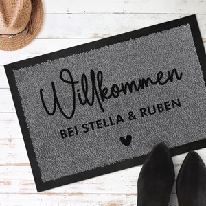 May include: Grey welcome mat with black text that reads "Willkommen bei Stella & Ruben" with a small black heart.