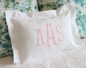 May include: White pillow with a pink monogram of the letters "AAS" embroidered on the front.