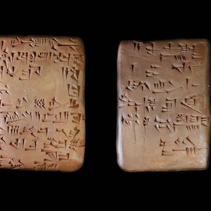 Könnte beinhalten: Zwei rechteckige Tontafeln mit Keilschrift, einer Form der alten Schrift, die auf ihre Oberflächen eingeritzt ist. Die Tafeln sind braun und haben eine raue Textur.
