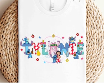 May include: White t-shirt with a custom name design featuring the characters from the movie Lilo & Stitch. The name "TYLANIE" is spelled out with each letter decorated with a different Stitch character. The design includes stars, flowers, and a pineapple.
