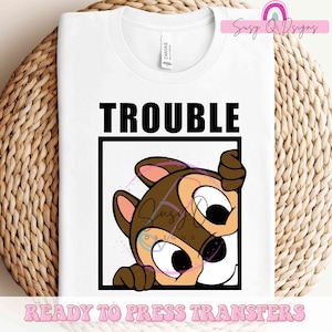 May include: White t-shirt with a black box around the text "TROUBLE" and a cartoon image of a brown chipmunk peeking out of the box. The text "READY TO PRESS TRANSFERS" is at the bottom of the shirt.