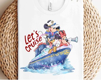 Könnte beinhalten: Ein weißes T-Shirt mit einem bunten Bild von Mickey Mouse und Minnie Mouse, die als Kapitän und Matrose auf einem blauen Kreuzfahrtschiff verkleidet sind. Der Text "Let's Cruise" ist in roten Buchstaben auf dem Shirt geschrieben.