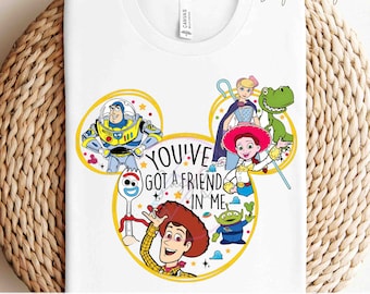 May include: A white t-shirt with a yellow Mickey Mouse head design featuring characters from the Toy Story movie franchise. The design includes Woody, Buzz Lightyear, Jessie, Rex, and the text "You've got a friend in me".